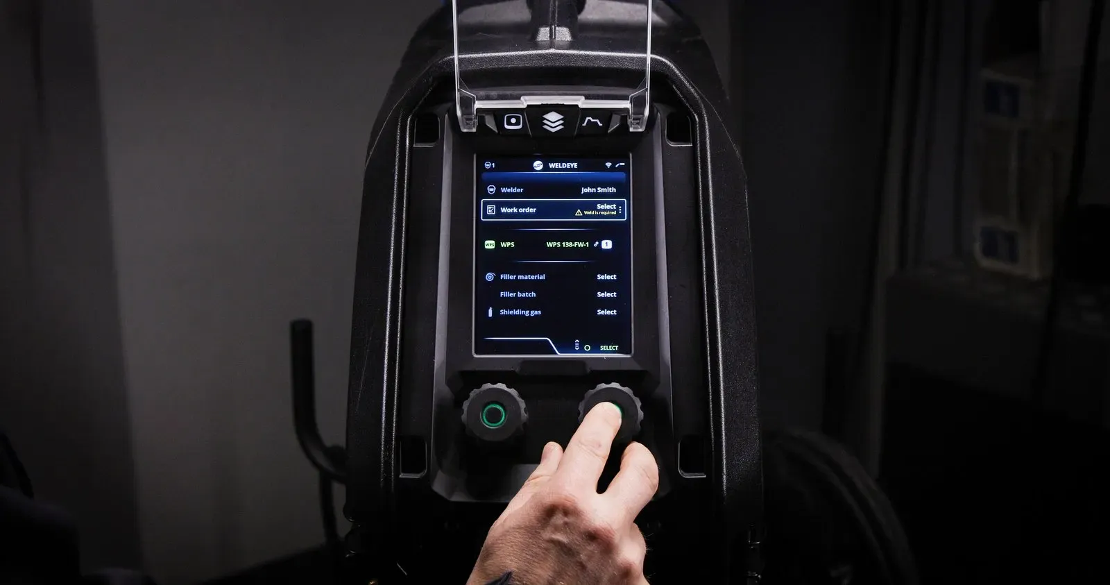 A hand on the Master M knobs, with the WeldEye screen on the display