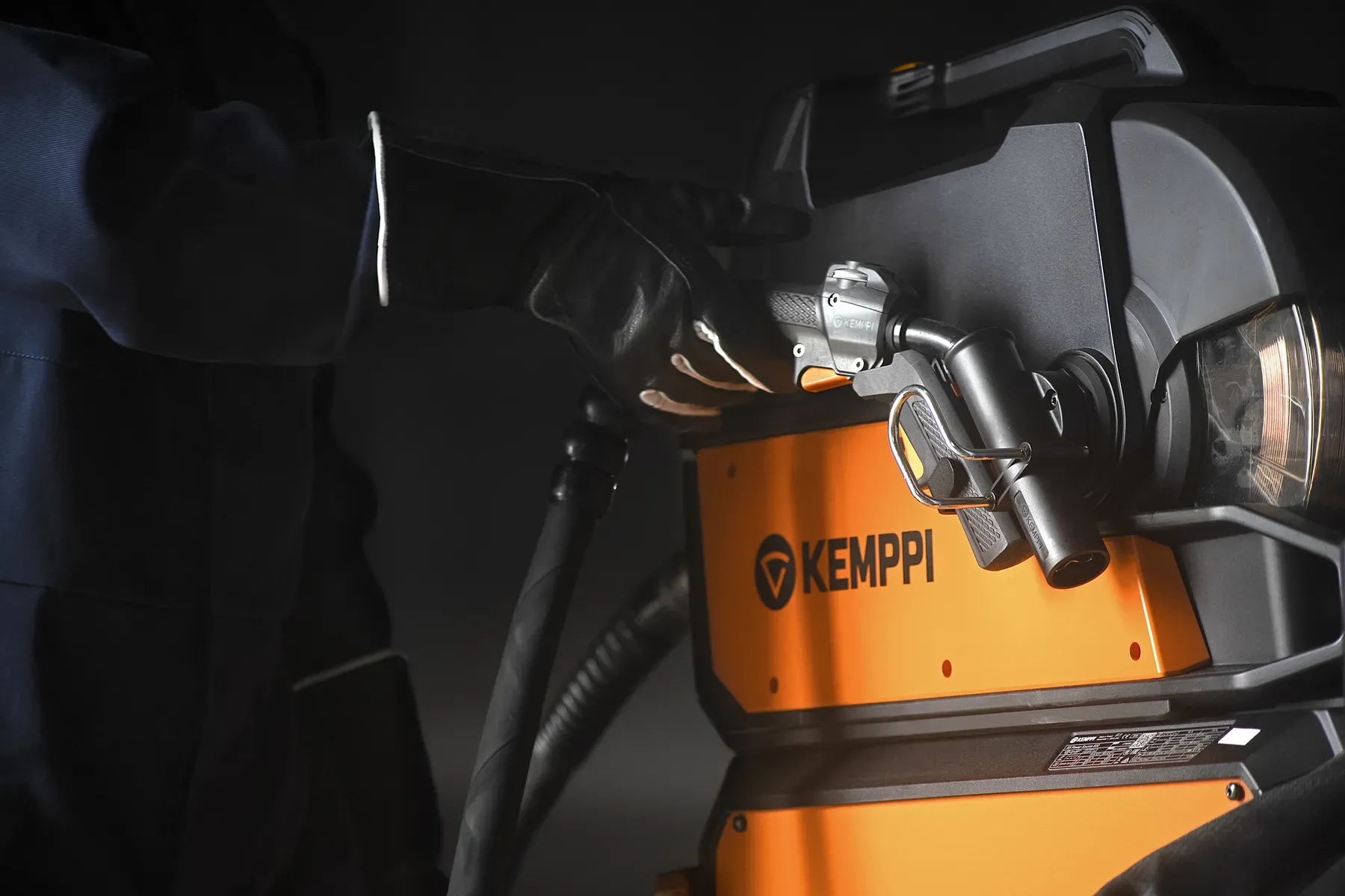 A gloved hand on the X5 wire feeder and welding gun
