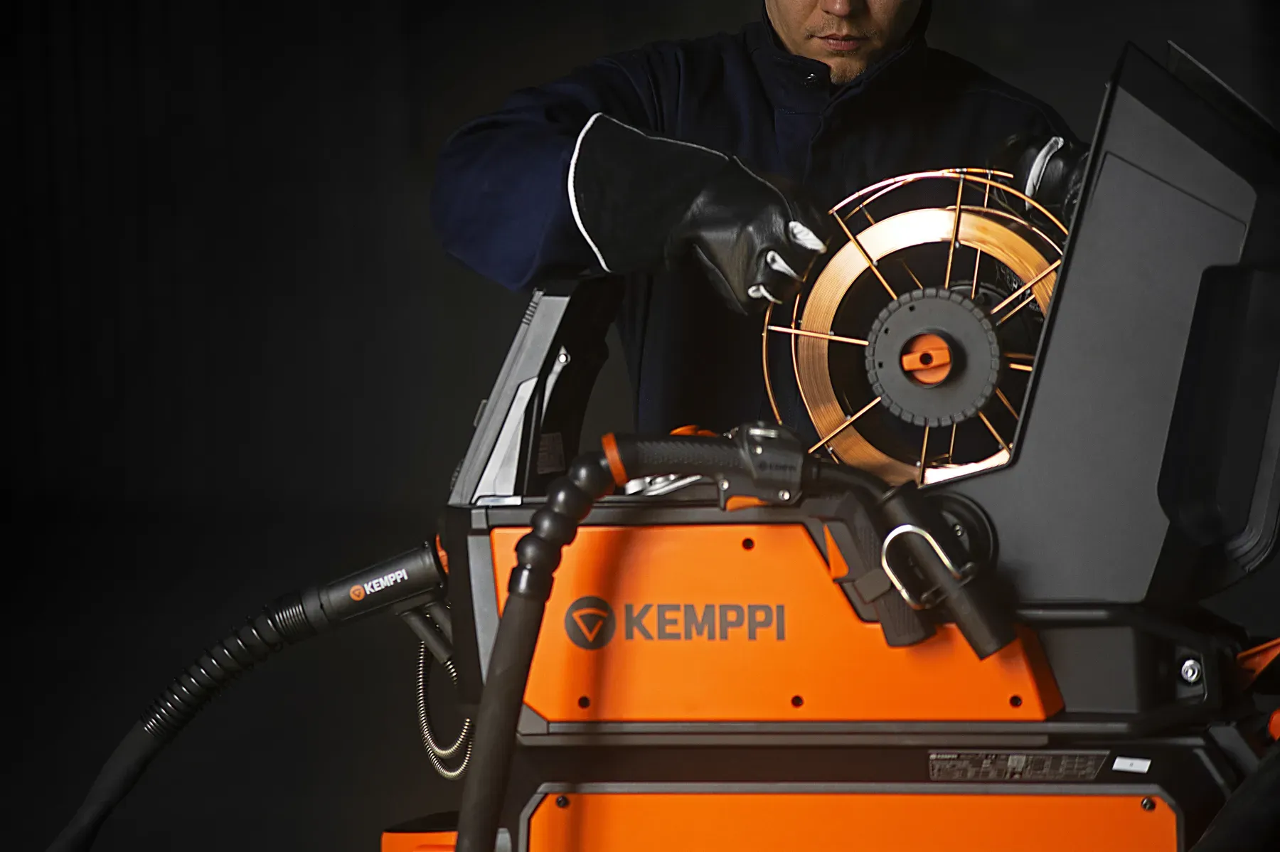 A gloved hand loading a wire spool into the X5 feeder